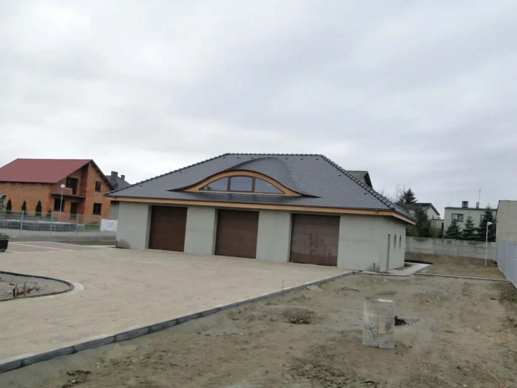 Wole oko na garażu z ciemną dachówką karpiówką — łukowa lukarna, widok frontalny