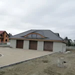 Wole oko na garażu z ciemną dachówką karpiówką — łukowa lukarna, widok frontalny