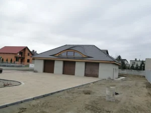 Wole oko na garażu z ciemną dachówką karpiówką — łukowa lukarna, widok frontalny