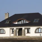 Efektowne wole oko z łukowym balkonem na domu w trakcie budowy — ciemna karpiówka — firma Wole Oko